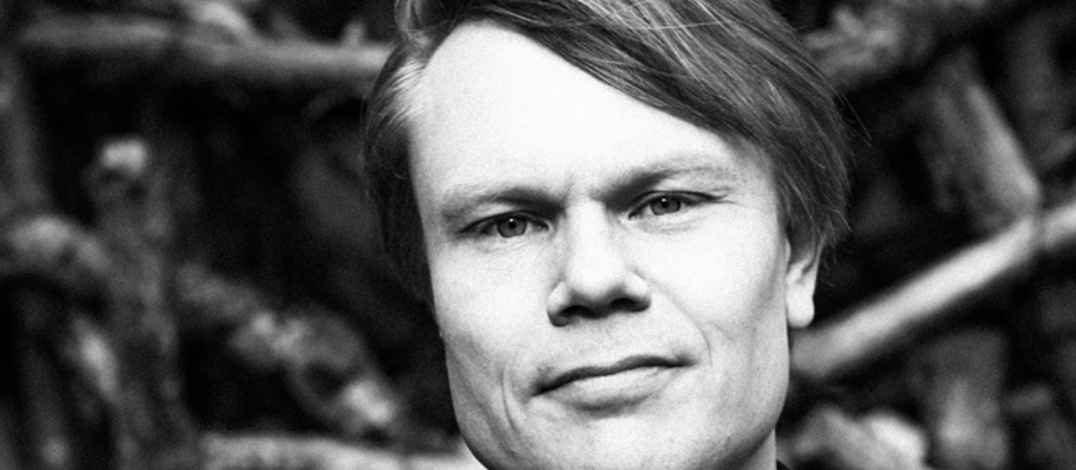 Peter Jensens ansigt i sort og hvid foran træer og grene