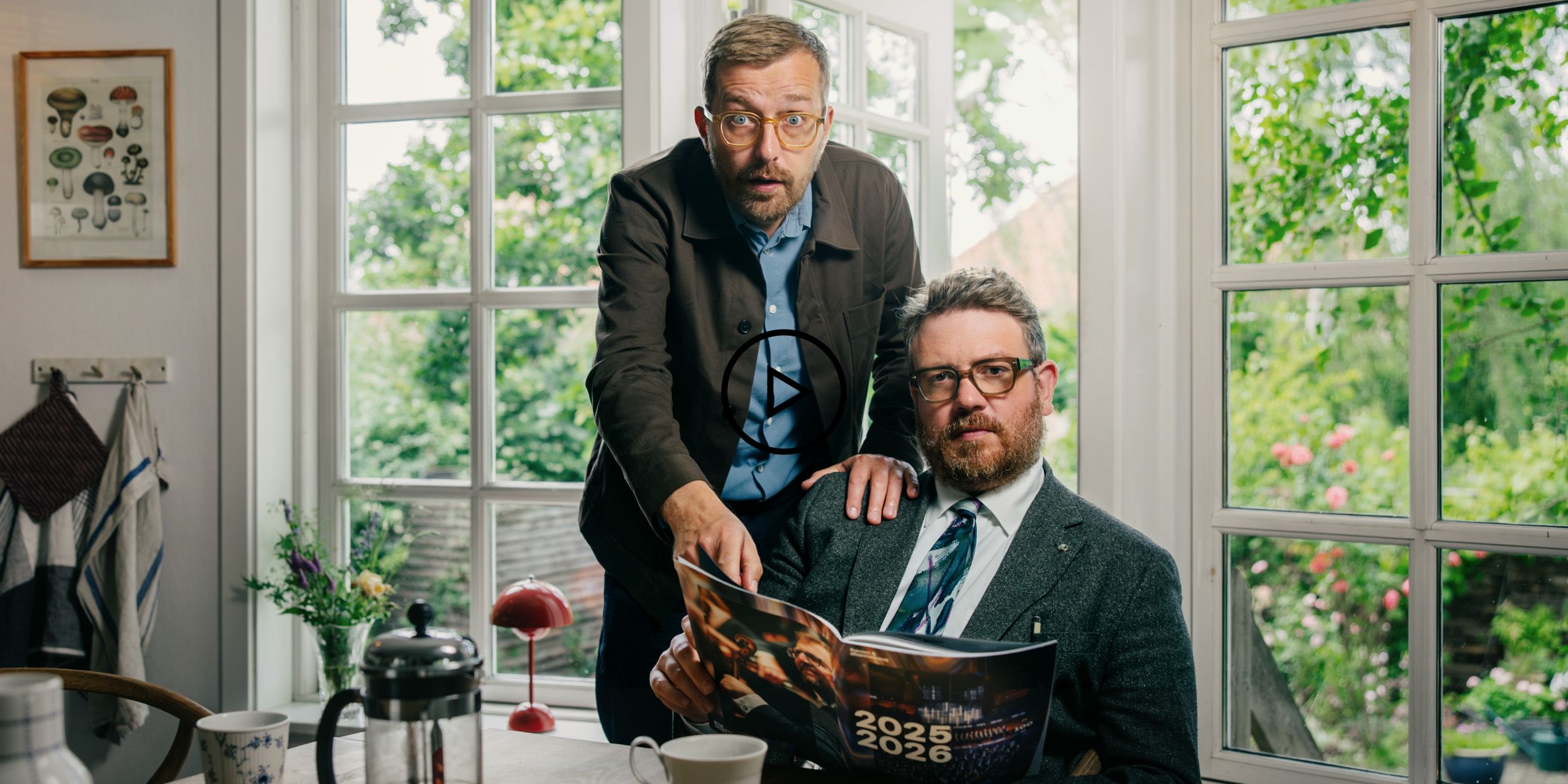 Video logo - Rasmus Bruun og Frederik Cilius sidder i et køkken og ser overrasket ud