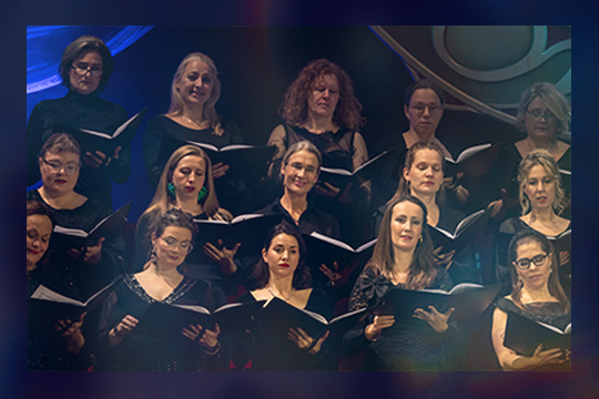 Et modent kort med femten kvinder koncentreret med sanghæfter i hænderne til Gaming X Symphony-koncerten i koncertsalen.