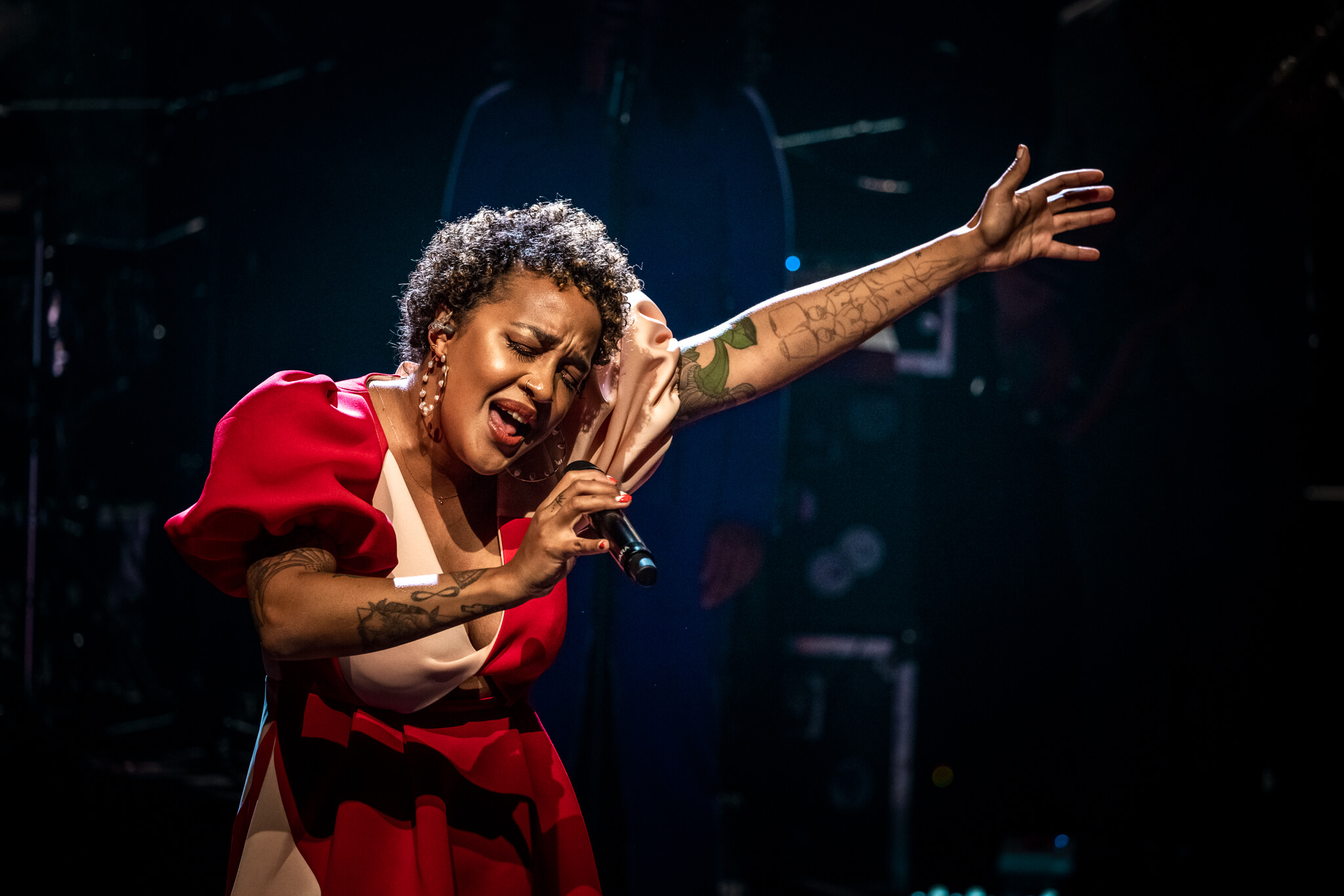Afroamerikanske afstamning Barbara Moleko iført rød elegant kjole synger dybfølt med lukkede øjne 