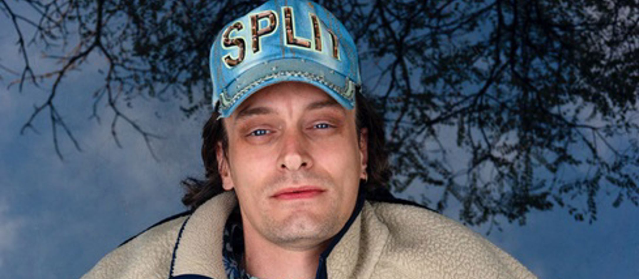 Casper Clausen med kasket og blålig baggrund