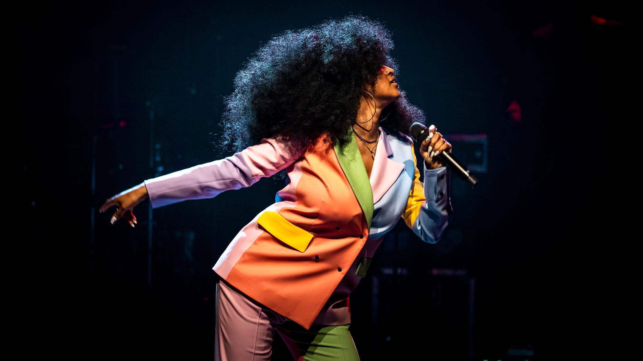 Iris Gold i profil performer i spraglet jakkesæt og stort afrohår ser tjekket ud