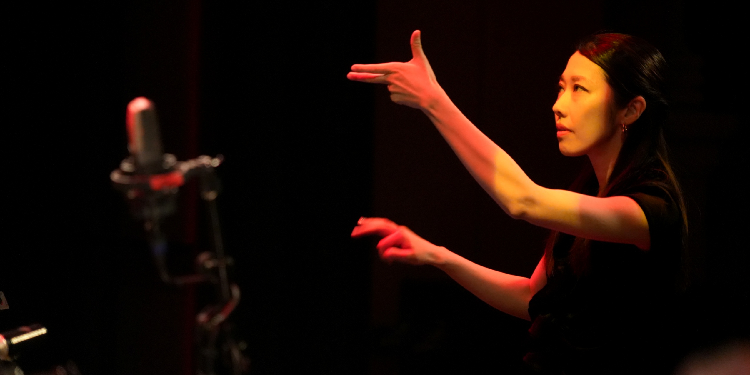 Kvinde med løftede arme der dirigere.